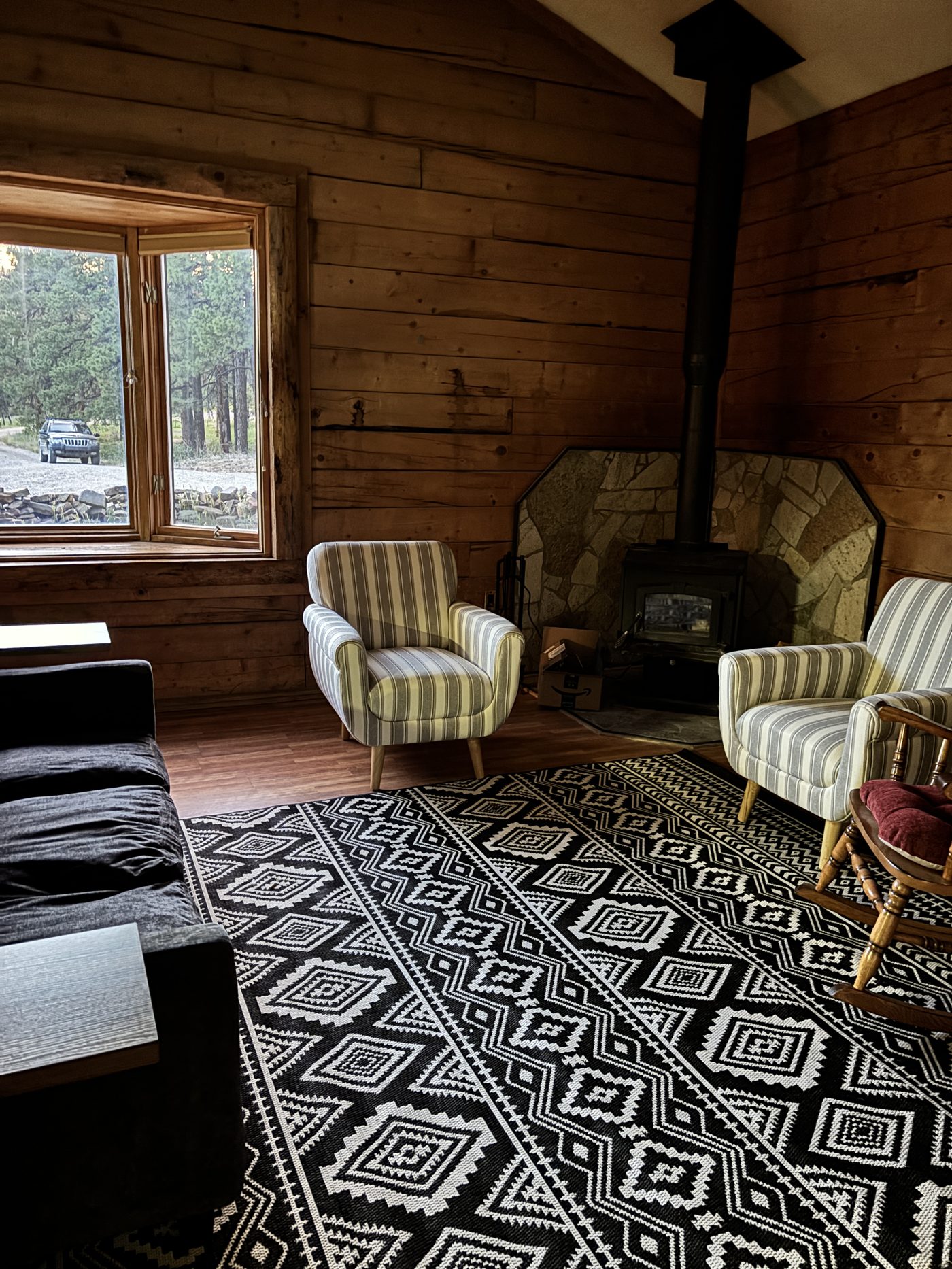 Wood-stove sitting nook with striped armchairs and a rocking chair